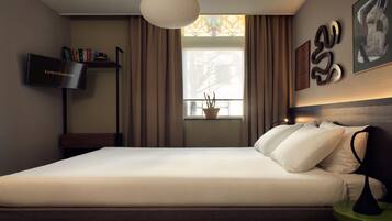 A neatly made bed in a hotel room with a flat-screen TV on a stand, a potted plant by the window, and abstract art on the wall.