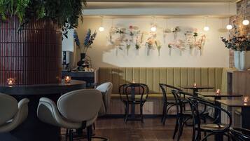 A restaurant interior with a booth seating area, round tables, and chairs.