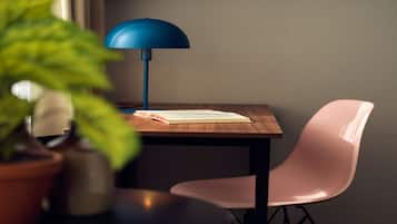 A wooden table with a blue lamp, a pink chair, and a book.