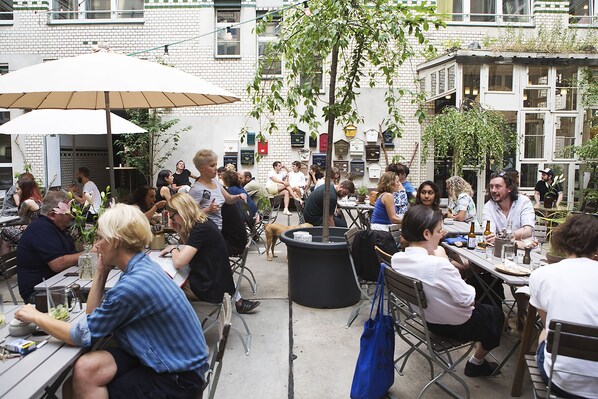 An outdoor café with tables and chairs, surrounded by buildings. - Michelberger Hotel Berlin (Berlin)