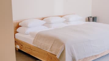 A bed with white bedding, a wooden headboard, and a grey rug.