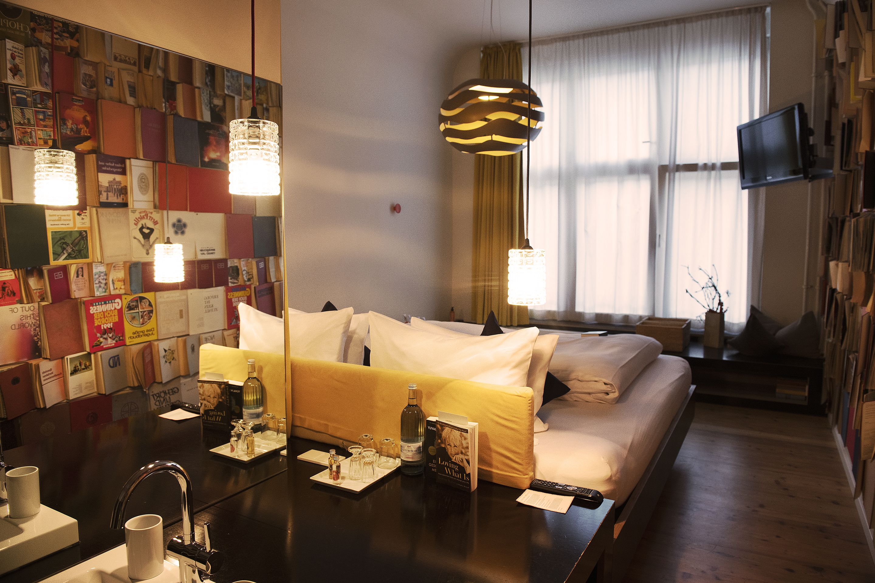 A hotel room with a bed, bedside table, and a wall decorated with various items.