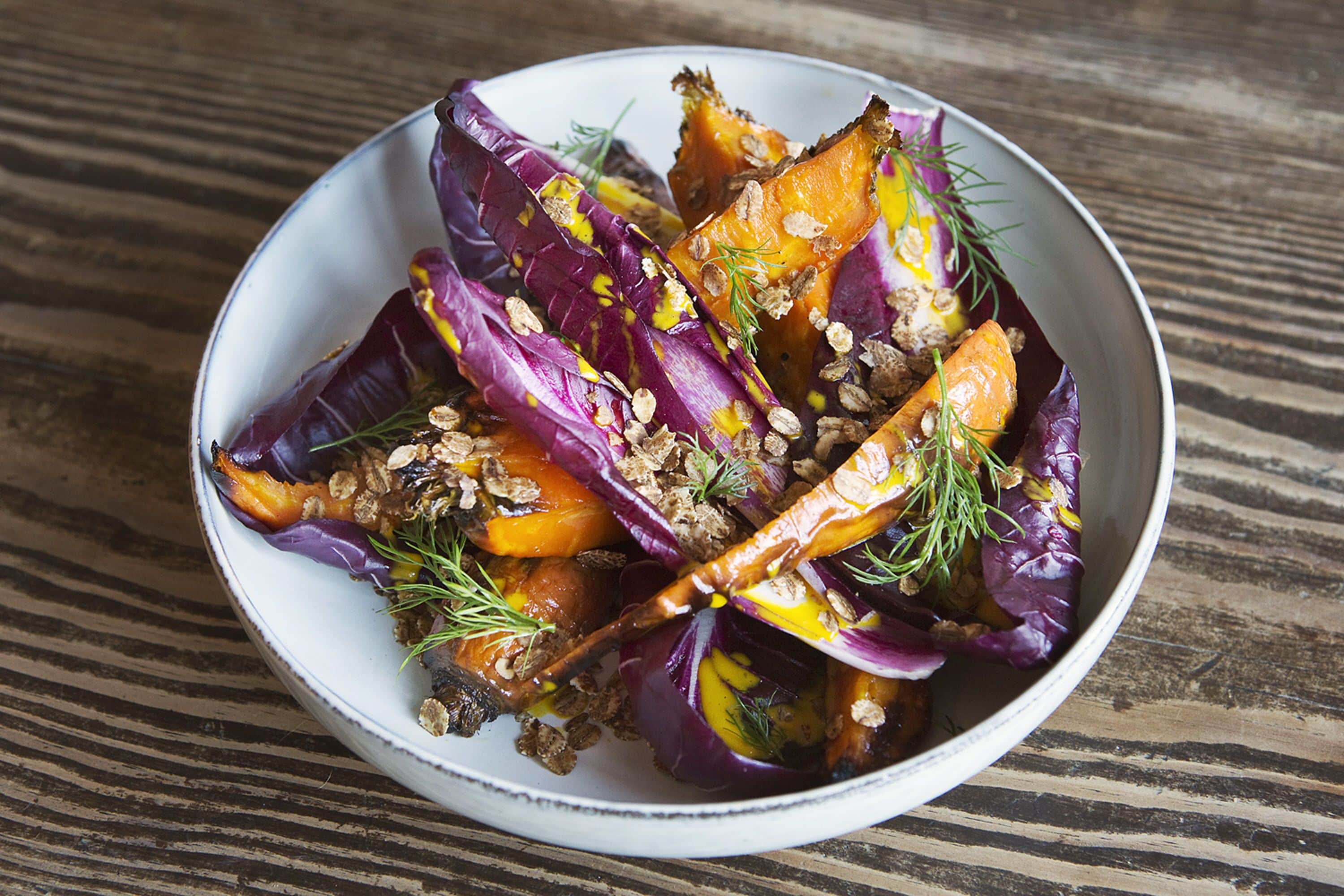 Un plat de légumes rôtis, comprenant du chou rouge et des carottes, agrémenté d’herbes et de noix.