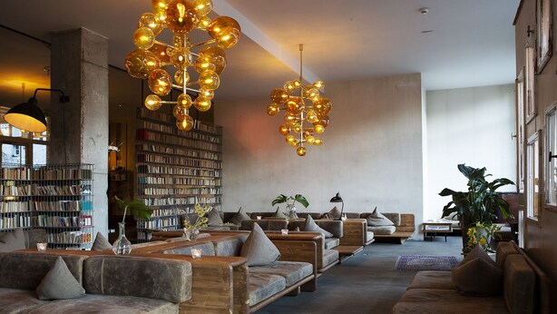 Una biblioteca amplia con varias zonas de estar, estanterías y una iluminación decorativa.