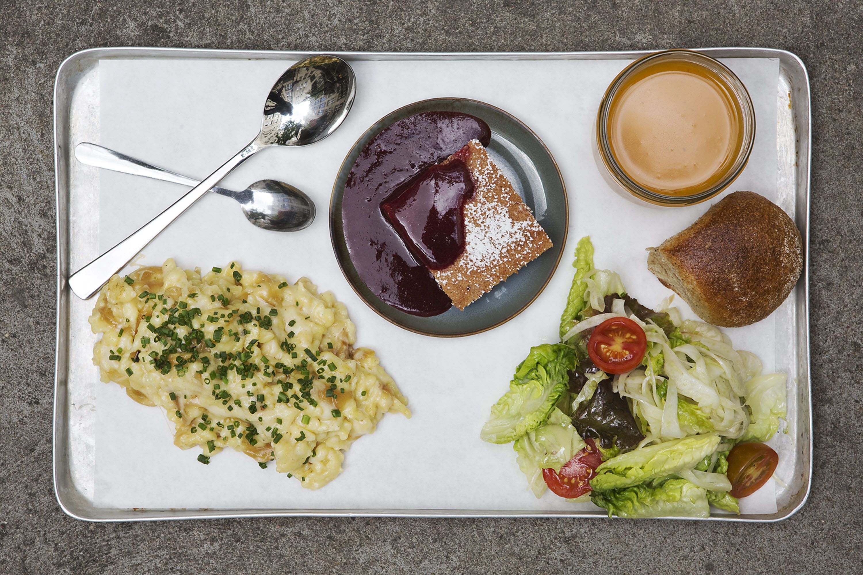 Una bandeja con macarrones, una porción de pastel, una ensalada y una tostada.