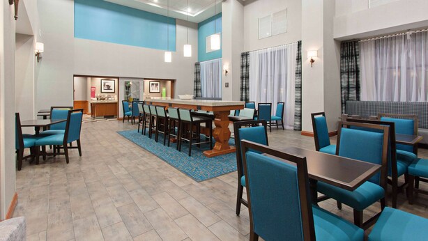 A hotel lobby with a central dining area, multiple seating arrangements, and a reception desk. - Hampton Inn & Suites Clovis-Airport North (Clovis)