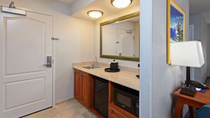 A compact hotel bathroom with a sink, mirror, and a small desk with a lamp. - Hampton Inn & Suites Clovis-Airport North (Clovis)