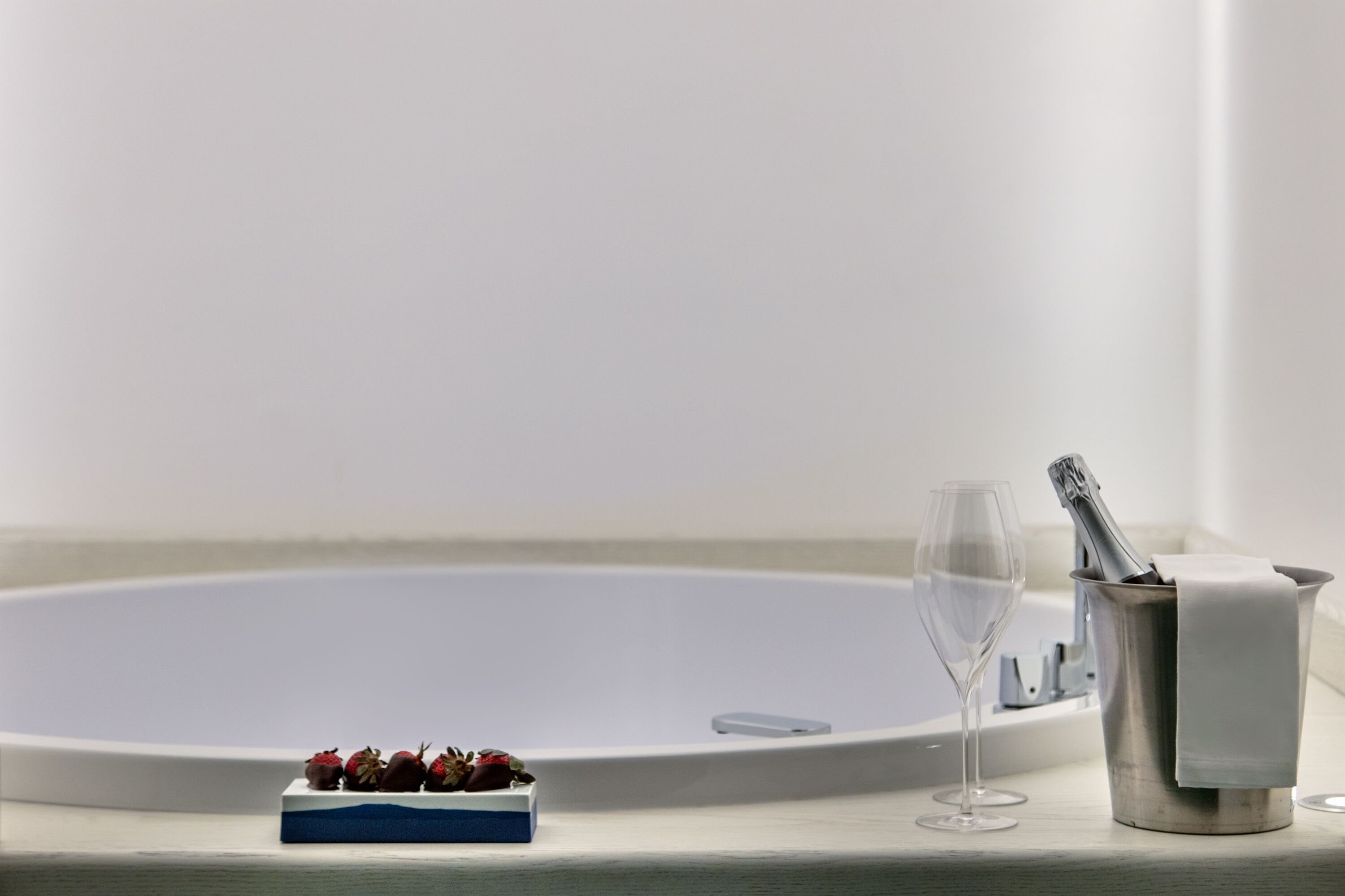 Eine Badewanne mit einem Glas Wasser und einer Schale Erdbeeren.