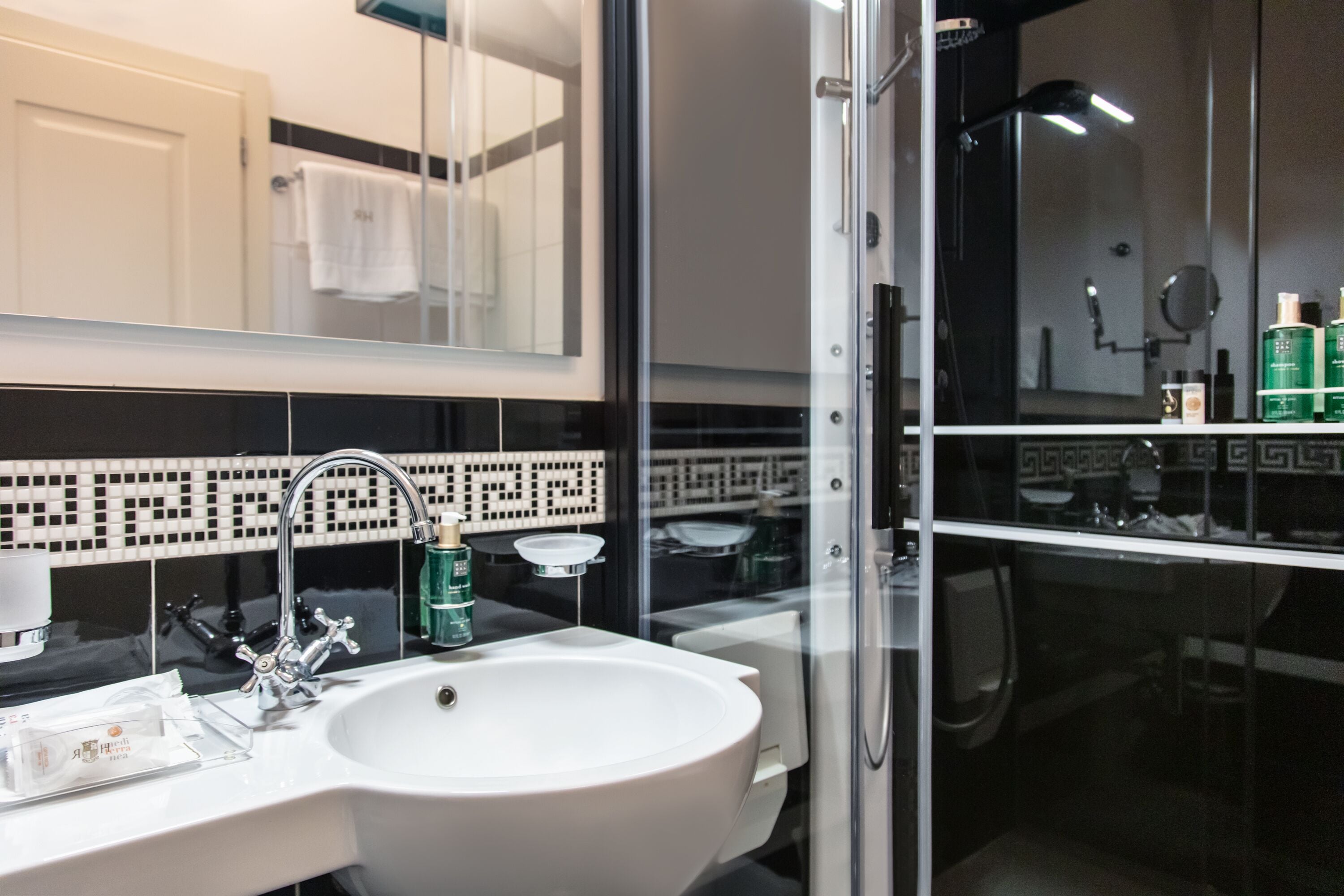 A modern bathroom with a white sink, a glass shower enclosure, and a mirror above the sink.