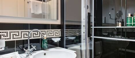 A modern bathroom with a white sink, a glass shower enclosure, and a mirror above the sink.