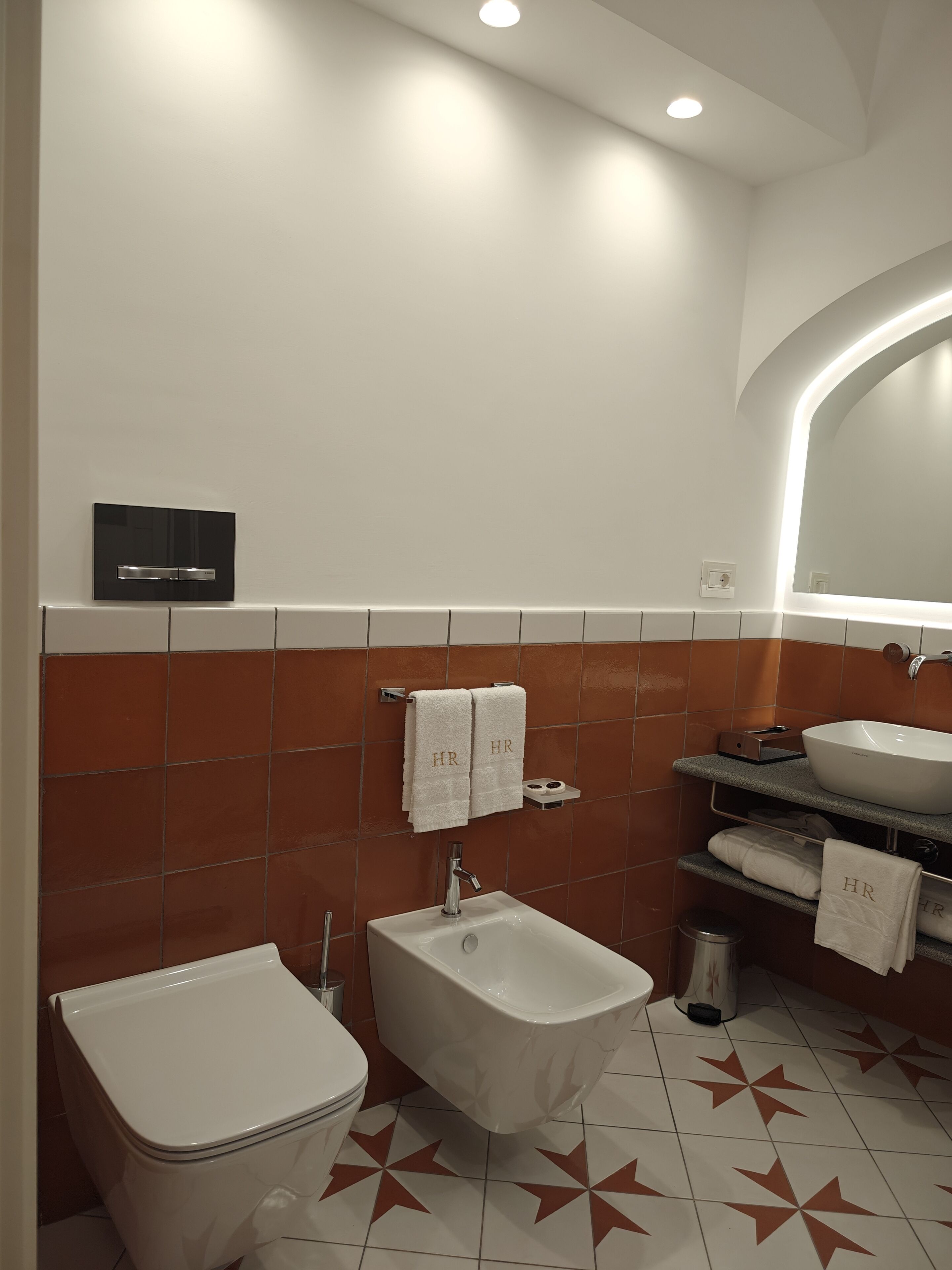 A modern bathroom with a bidet, a toilet, a sink, and a mirror.