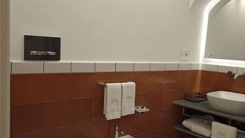 A modern bathroom with a bidet, a toilet, a sink, and a mirror.