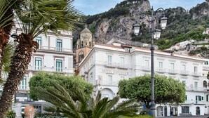 A hotel with a dome and a bell tower, surrounded by lush greenery and a mountainous backdrop. - Hotel Residence - Amalfi (Amalfi)