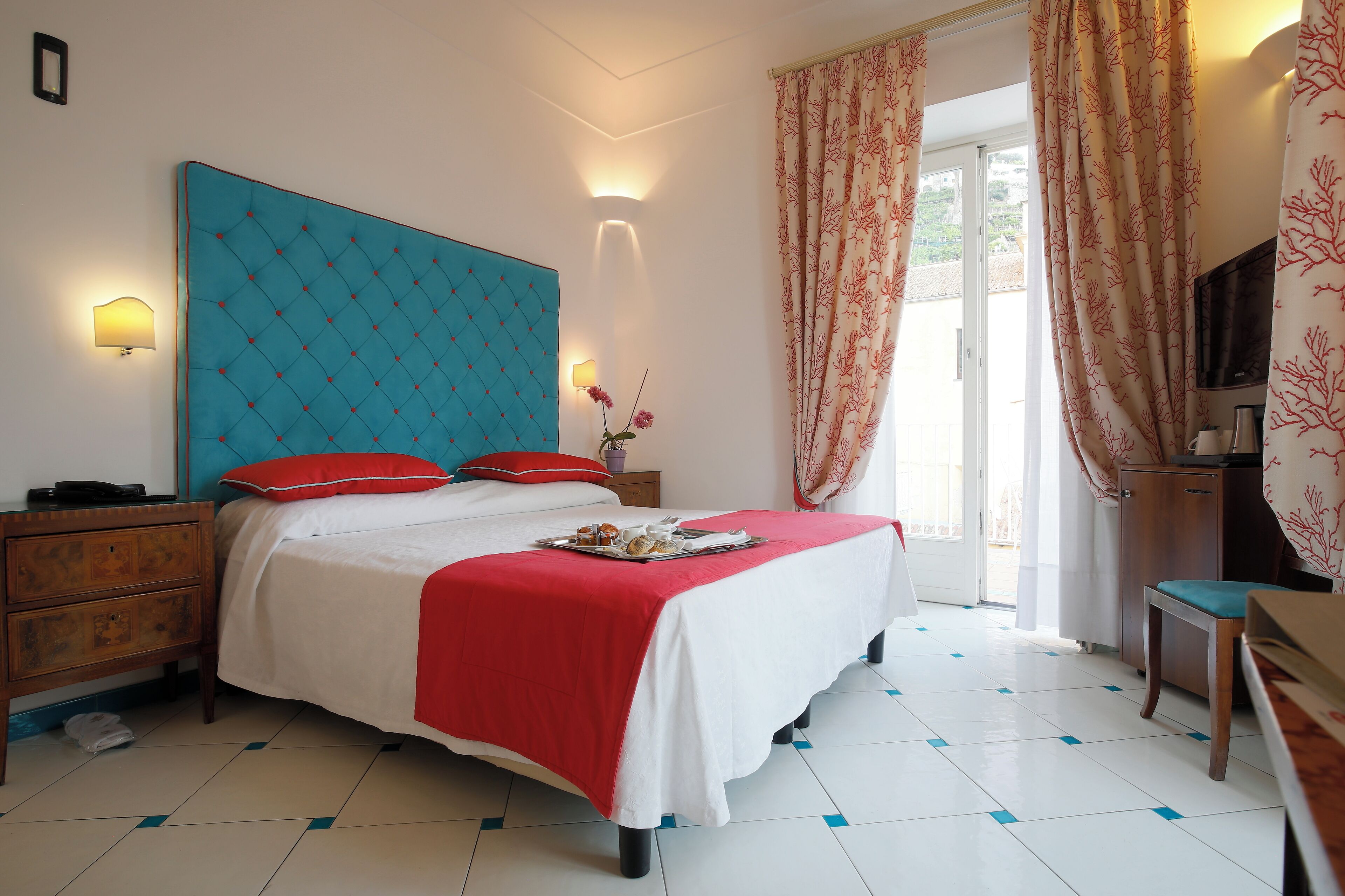 A bedroom with a large bed, a wooden nightstand, a desk, and a chair.