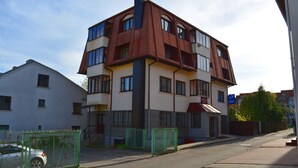 A multi-story building with a unique architectural design, featuring a combination of white and brown colors, and a visible entrance with a red awning. - Jeruzale Hotel (Vilnius)