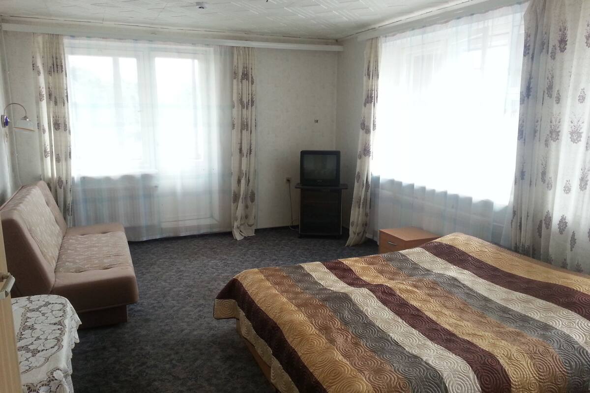 Une chambre d’hôtel avec un lit, un canapé, une télévision et des rideaux.