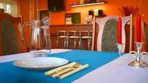 A dining table set with a pitcher, plate, cutlery, and candle holder. - Jeruzale Hotel (Vilnius)