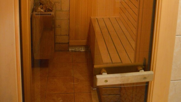 A wooden sauna with a bench and a small bench with a towel. - Jeruzale Hotel (Vilnius)