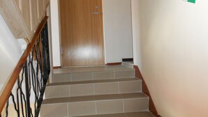 A staircase with a wooden handrail and a green-tiled wall. - Jeruzale Hotel (Vilnius)