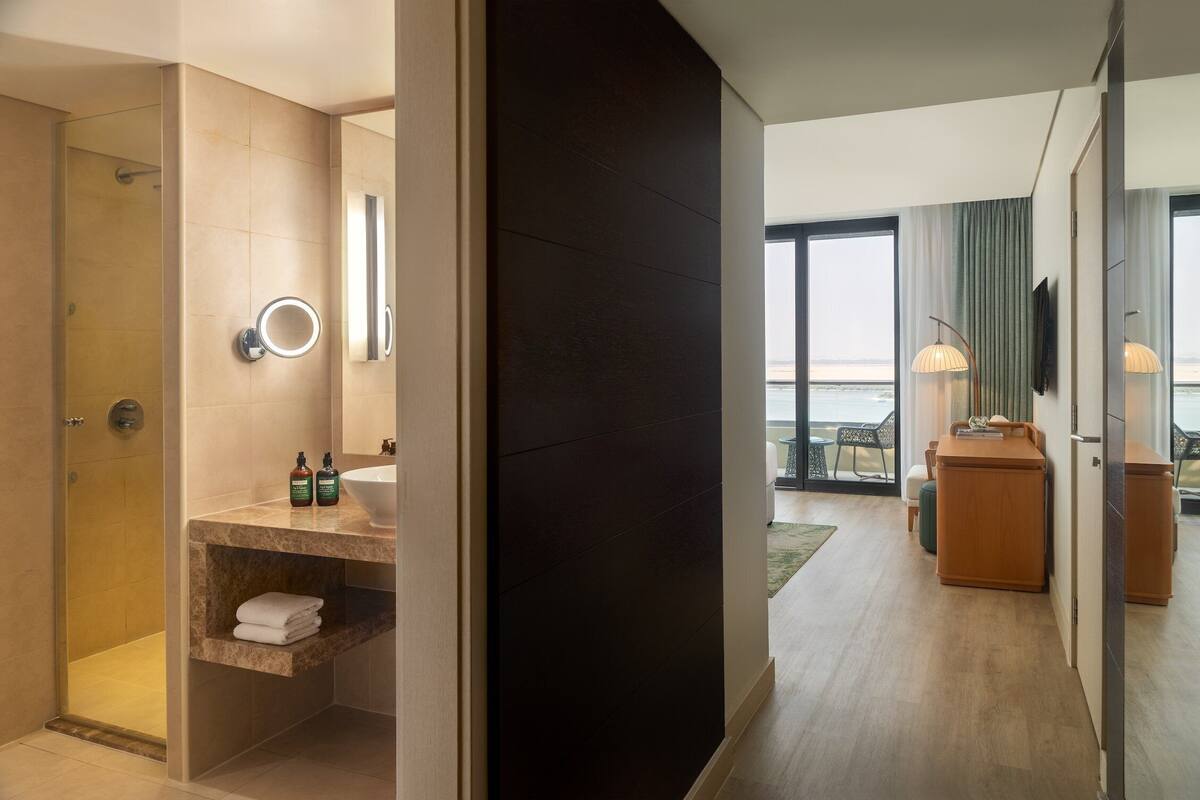 Un baño de hotel moderno con ducha, tocador y vista al mar.