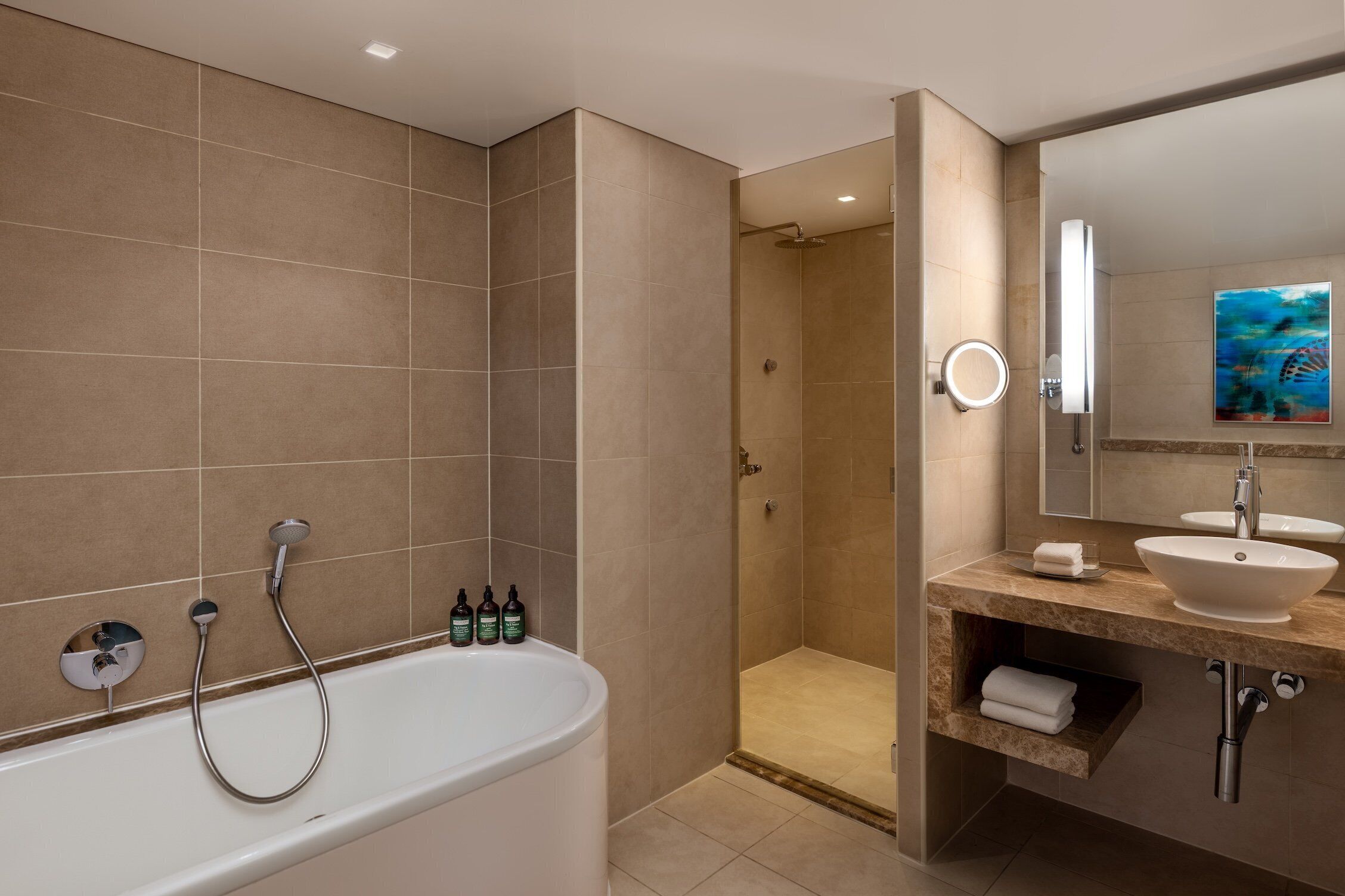 A modern bathroom with a bathtub, shower, and vanity with a sink and mirror.