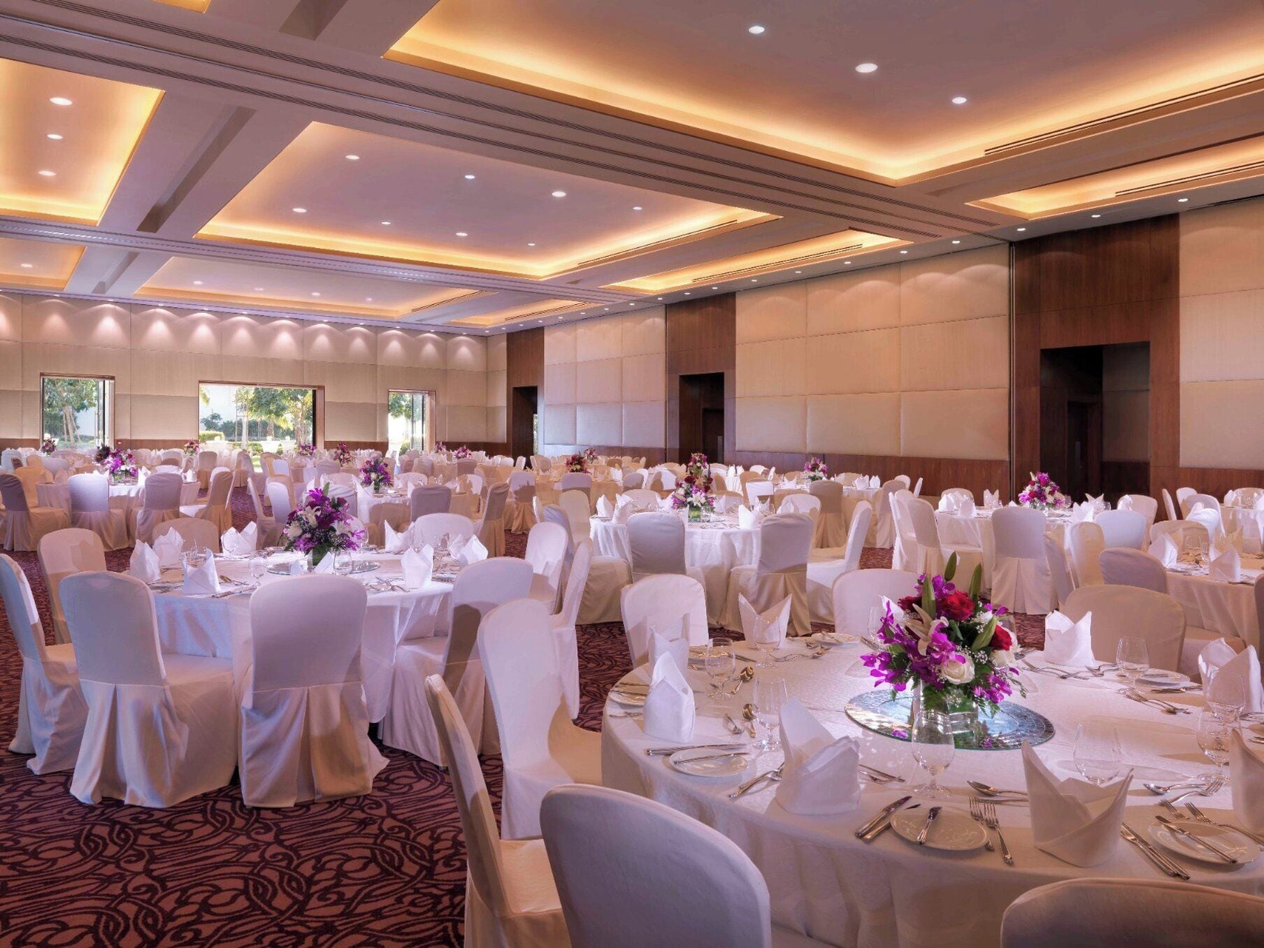 Une salle de banquet avec des tables rondes, des nappes blanches et des chaises, disposées pour un événement formel.