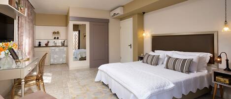 Habitación de hotel con una cama grande, un escritorio y una silla. Se ve un baño por una puerta abierta.