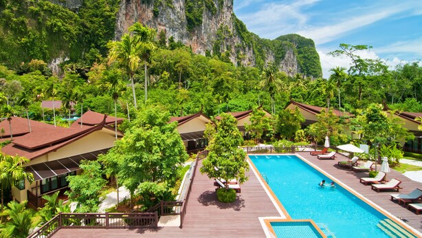 Ein Resort mit Schwimmbad, Holzterrasse und Villen, umgeben von üppiger Vegetation und einer Klippe.