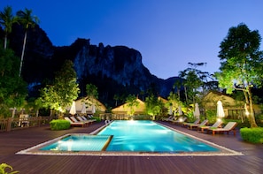 A swimming pool with lounge chairs and umbrellas, surrounded by greenery and a mountain backdrop. - Aonang Phu Petra Resort Krabi (Krabi)