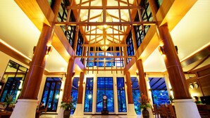 Eine großzügige Lobby mit hohen Decken, massiven Holzsäulen und einer zentralen Uhr.