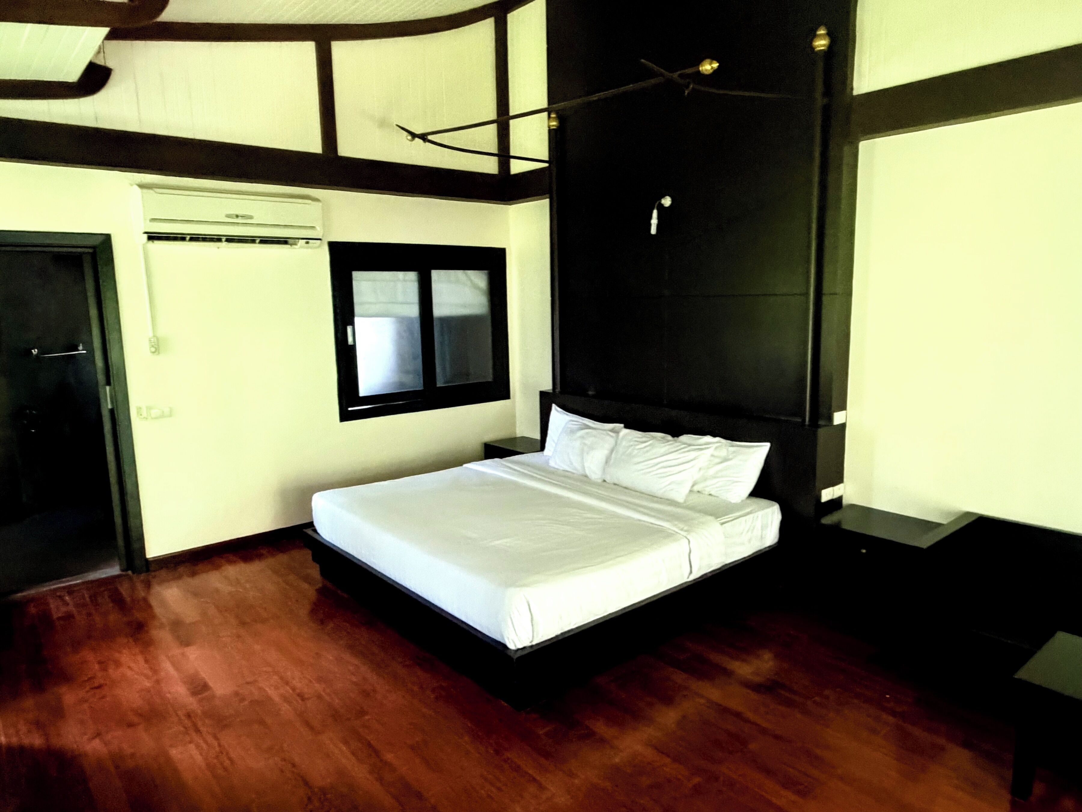 Un dormitorio con cama, ventana, aire acondicionado y puerta.