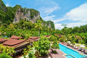 A resort with a swimming pool, palm trees, and a cliff in the background. - Aonang Phu Petra Resort Krabi (Krabi)