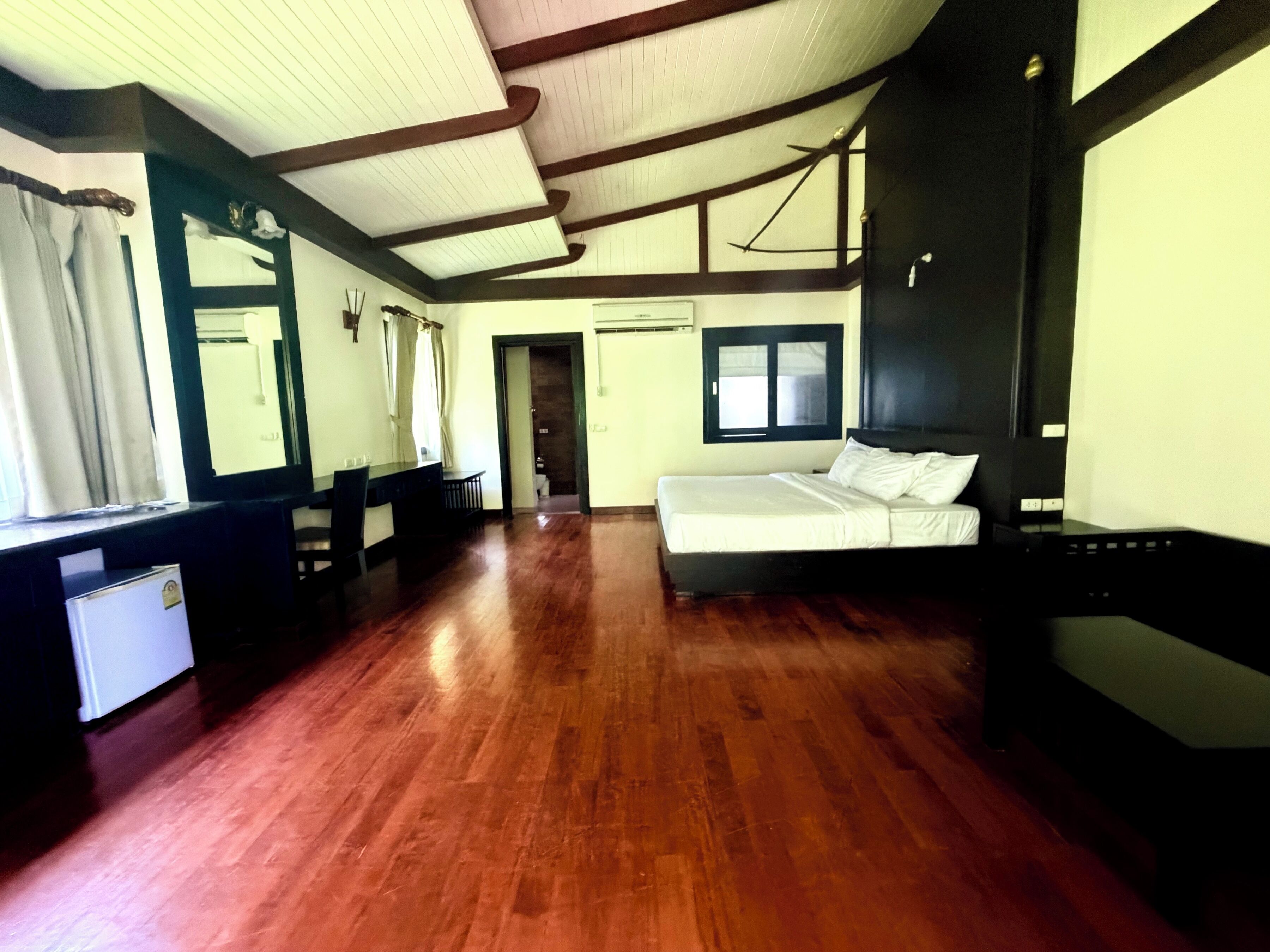Una habitación con una cama, un escritorio y una silla. Cuenta con una ventana y una puerta.