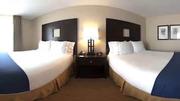 A hotel room with two beds, a nightstand, a lamp, and framed pictures on the wall.