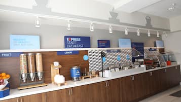 A breakfast bar with labeled dispensers for fruit and cereal, a coffee machine, and a sign promoting a healthy breakfast.