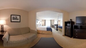 A hotel room with a sofa, a bed, a TV, and a mirror. - Holiday Inn Express Hotel & Suites Albuquerque Airport by IHG (Albuquerque)