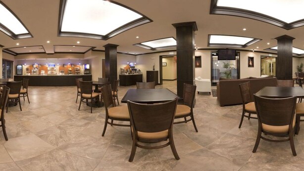 A spacious lobby with a central bar area, multiple seating arrangements, and a high ceiling with skylights. - Holiday Inn Express Hotel & Suites Albuquerque Airport by IHG (Albuquerque)