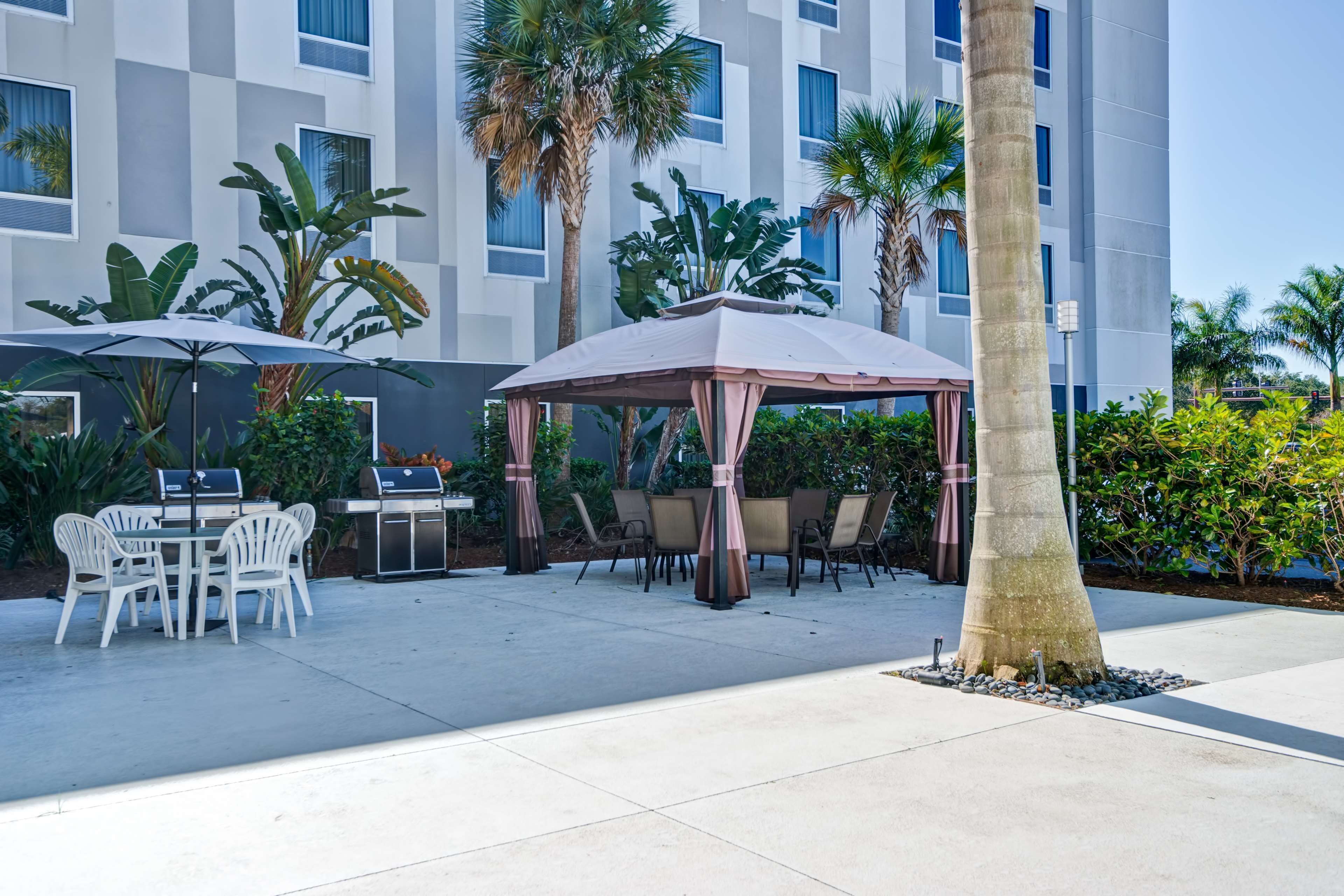 Un patio al aire libre con mesas, sillas, una parrilla y un pabellón.