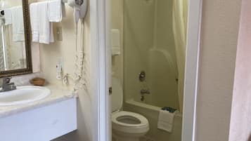 A bathroom with a sink, mirror, hairdryer, and shower.
