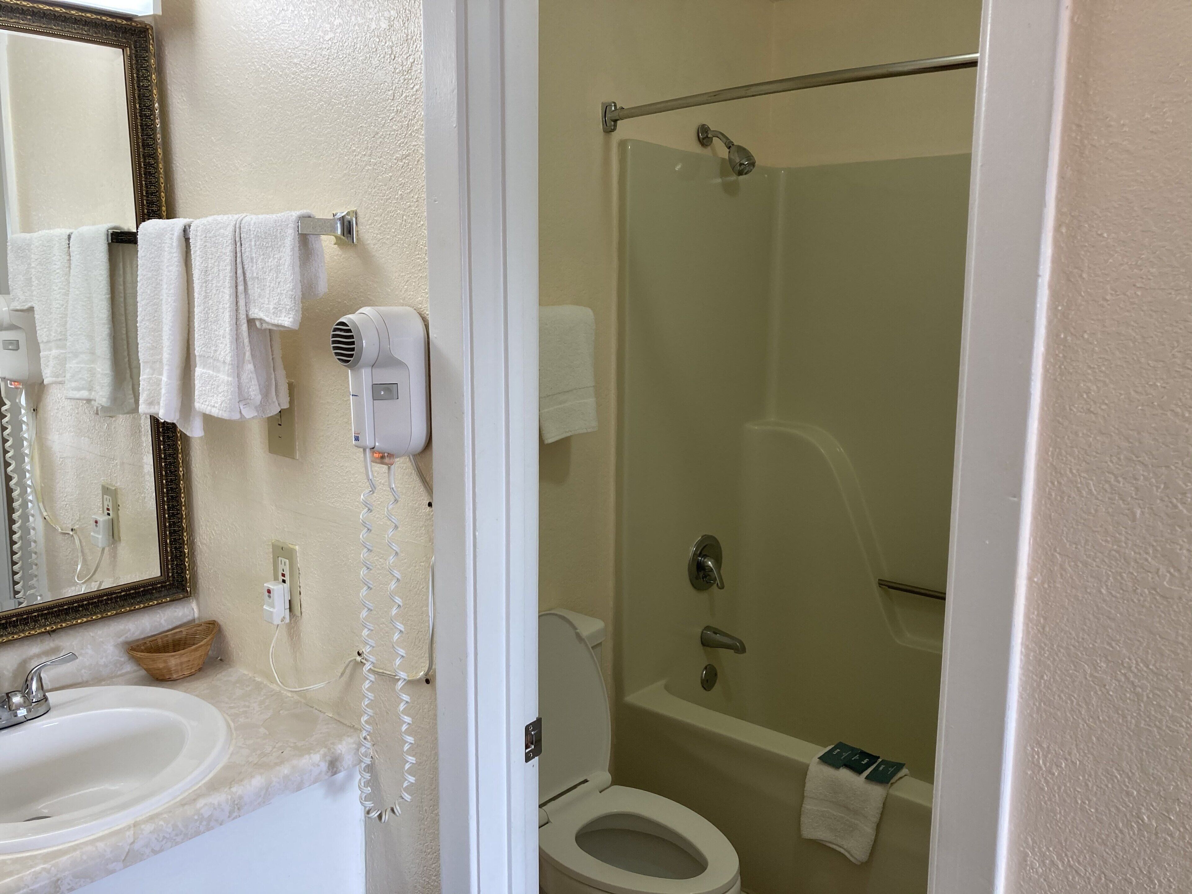 Un baño con lavamanos, espejo, toallero, secador de pelo y zona de ducha.