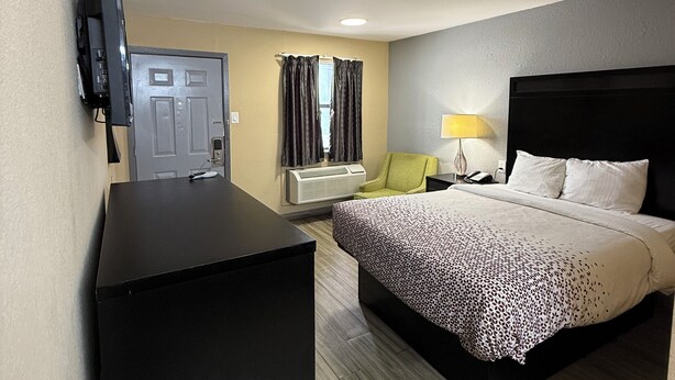 A hotel room with a bed, a desk, a TV, a lamp, and a door. - Travel Inn Hazen (Hazen)