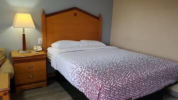Een hotelkamer met een houten bed, wit beddengoed, een bedlampje, een telefoon en een nachtkastje van hout.