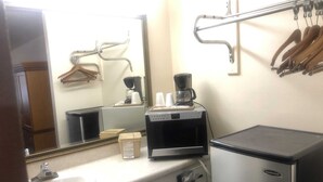 A compact hotel bathroom with a sink, a coffee maker, a mirror, and a small refrigerator. - Travel Inn Hazen (Hazen)
