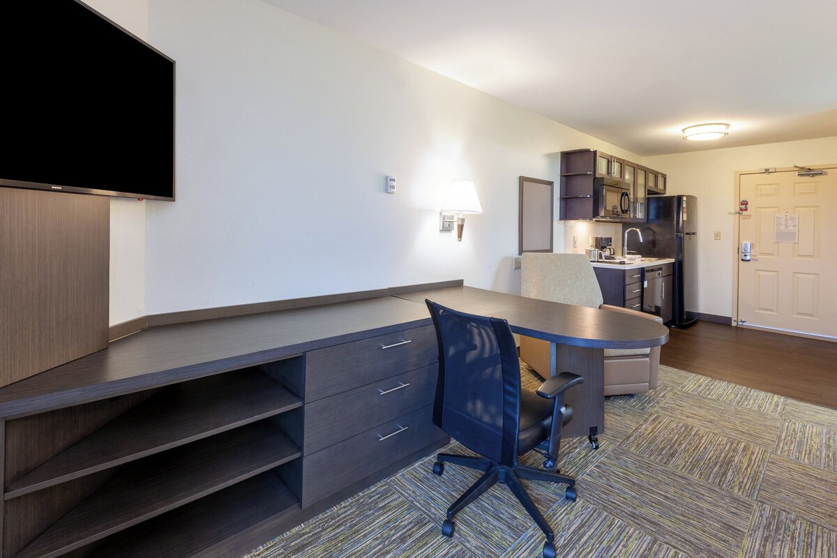 A modern kitchenette with a refrigerator, microwave, and stove.