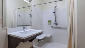 A bathroom with a white sink, a mirror, a shower with a handheld showerhead, and a towel rack.