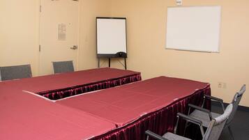 Un salón de conferencias con una mesa larga, sillas, una pizarra y una puerta.