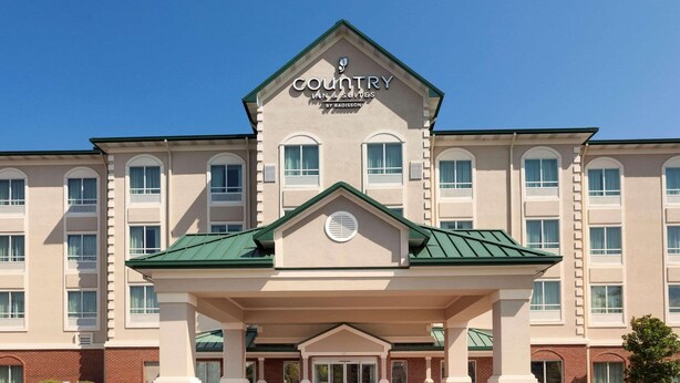 Ein Country Inn & Suites by Radisson Gebäude mit zentralem Eingang, zahlreichen Fenstern und einem begrünten Dach.