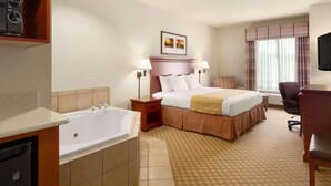 Ein Hotelzimmer mit einem großen Bett, einem separaten Badezimmer mit einer Badewanne, einem Schreibtisch und einem Fernseher.