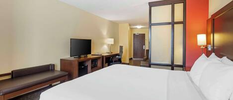 Habitación de hotel con una cama grande, un escritorio con una silla, un televisor y una ventana con vistas al exterior.