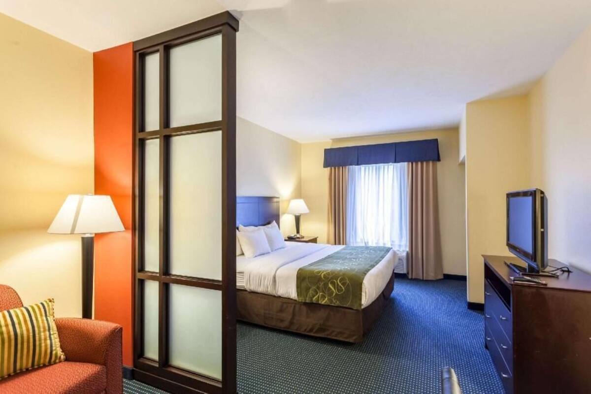 A hotel room with a bed, a television, a desk, and a chair.